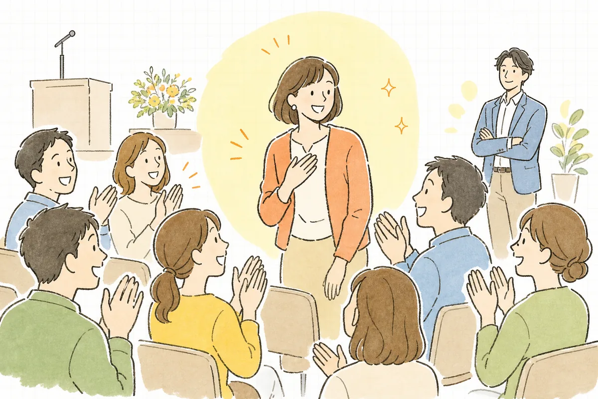表彰を終えて席に戻る受賞者を、同僚たちが笑顔で迎えている会場の後方から、その様子を見守っているイベント制作ディレクター