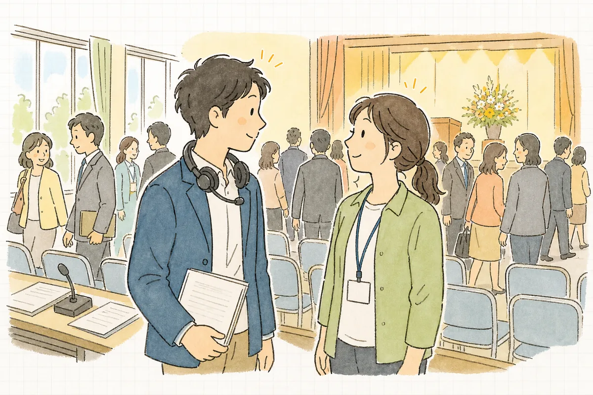式典が定刻どおりに終わった会場の後方で、進行席のディレクターとスタッフが穏やかにうなずき合っている場面
