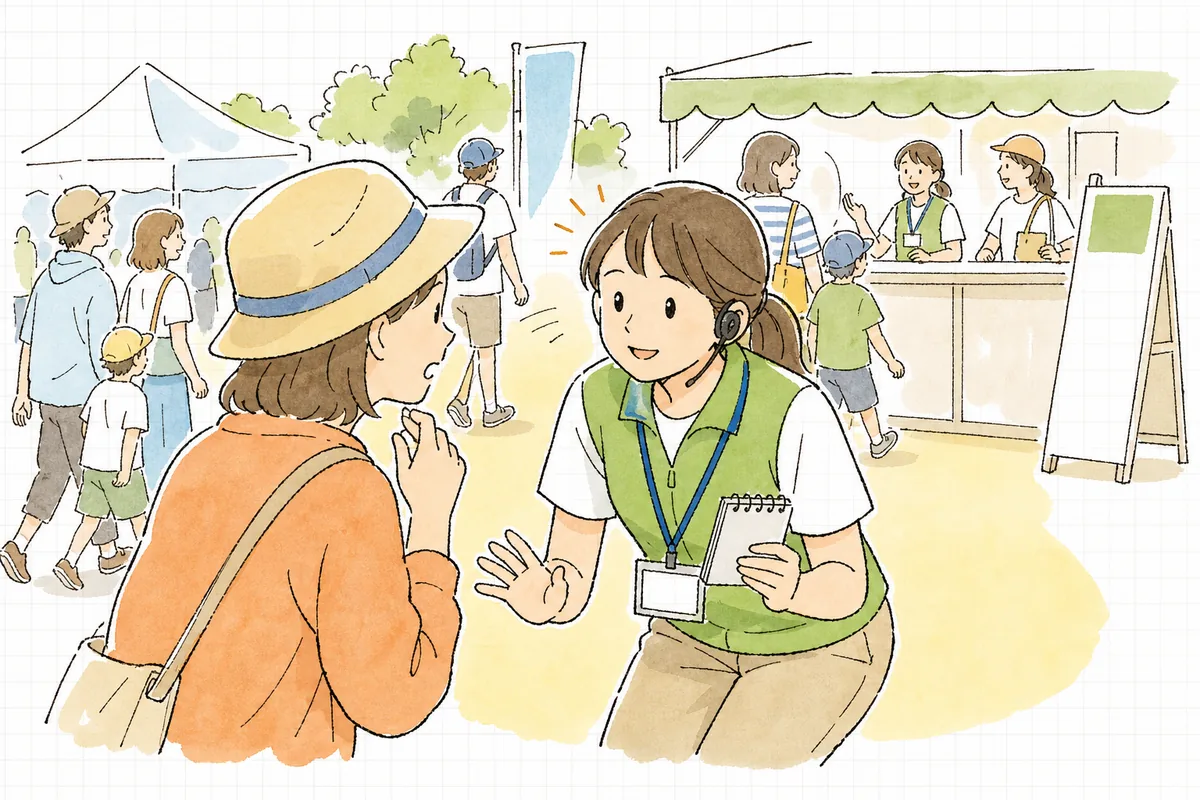 混み合うイベント会場の一角で、来場者の話を少し身をかがめて真剣に聞きながら、片手にメモとインカムを持って落ち着いて対応するイベントスタッフの様子